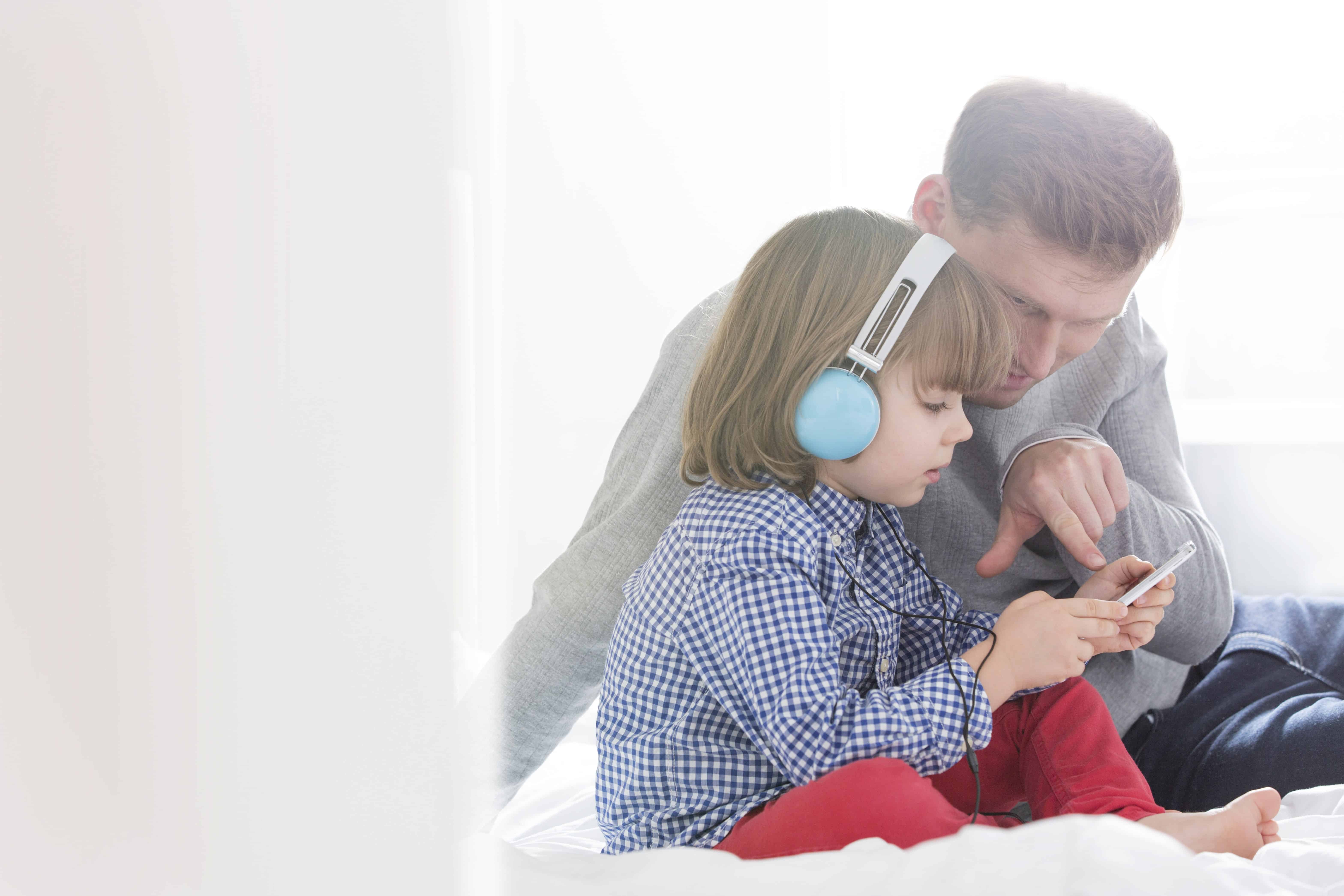 Child with headphones listening to music with father
