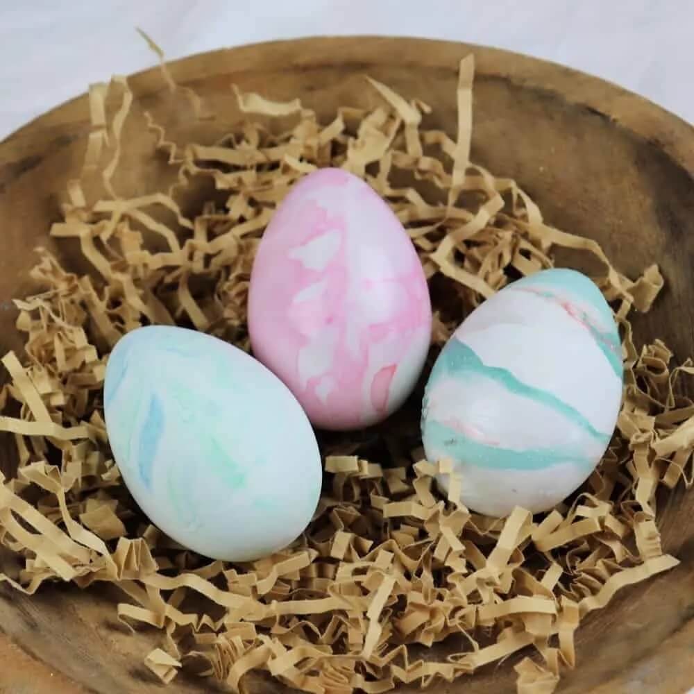 3 marble look easter eggs sitting on brown shredded paper