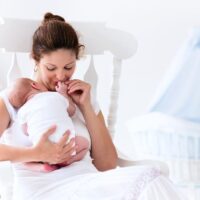 woman holding newborn in rocking chair