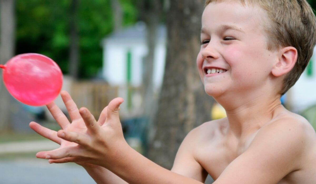 boy trying to catch a water balloon without busting it