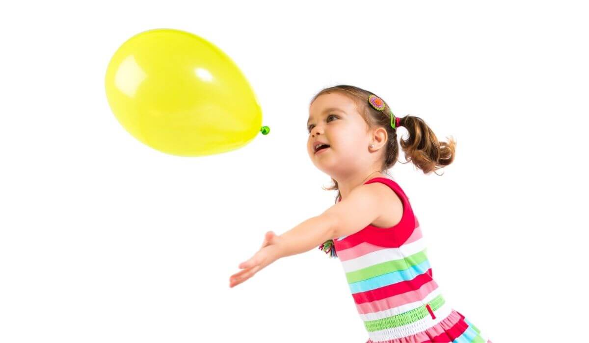 little girl hitting yellow balloon up in the air