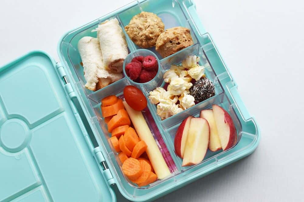 teal bento lunch box with a variety of healthy snacks