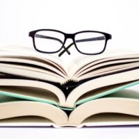 books about decluttering stacked with reading glasses