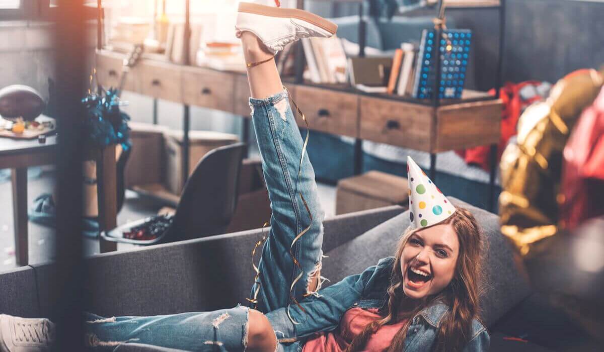 a woman with a party hat on with her leg in the air on the couch