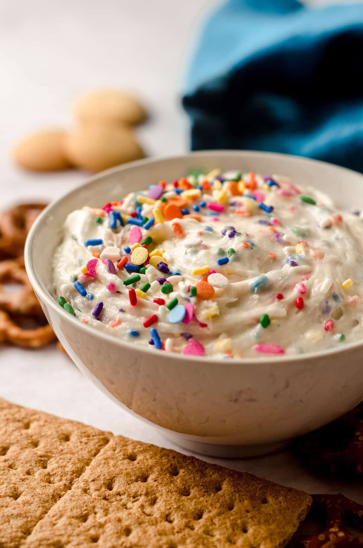 cake batter dip in a bowl with sprinkles with graham crackers