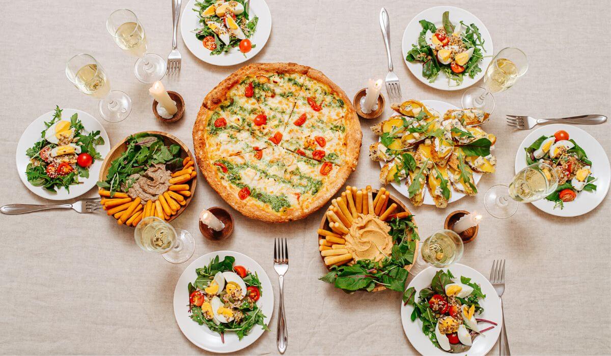 table with pizza, side dishes and wine