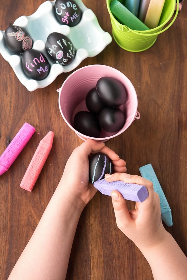 child drawing with chalk on black chalkboard paint easter eggs