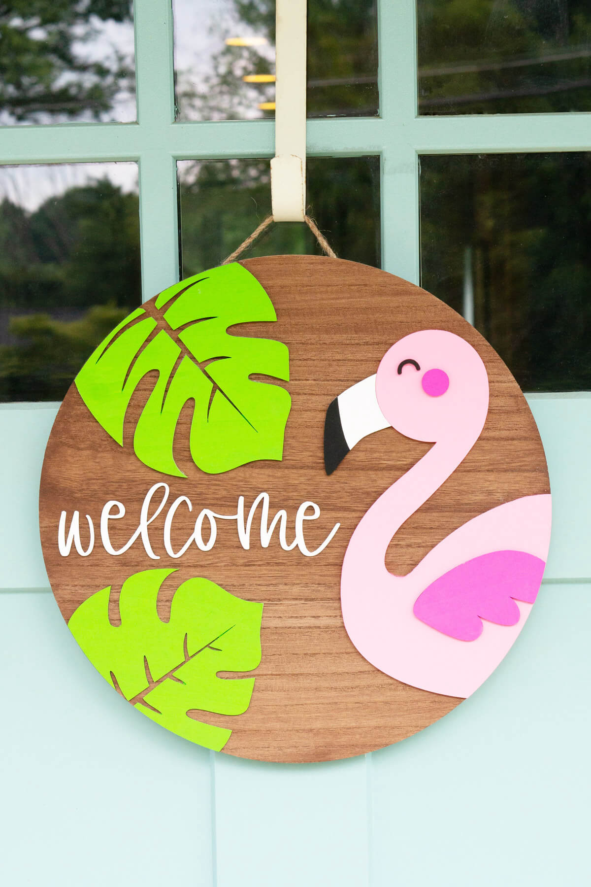 hanging wooden welcome sign with flamingo and leaves