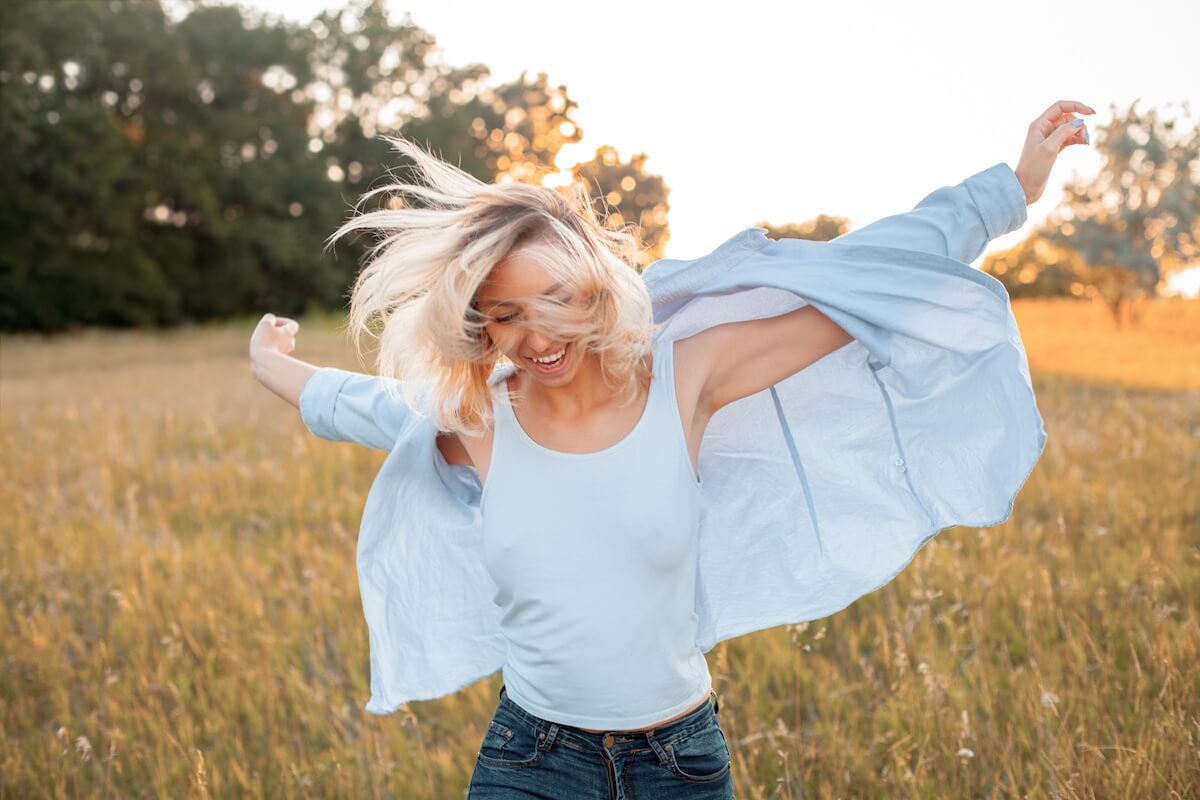 happy woman running around outdoors as the sun sets in the background.