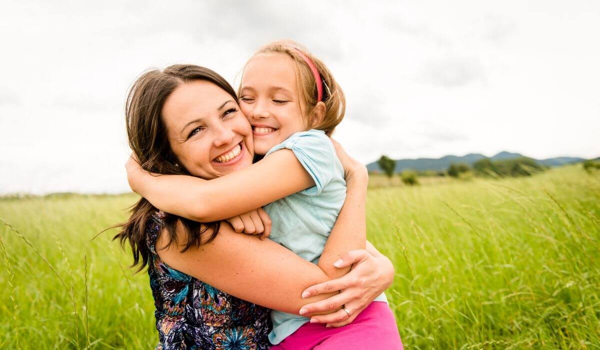 Mother hugging her daughter outdoors in a field