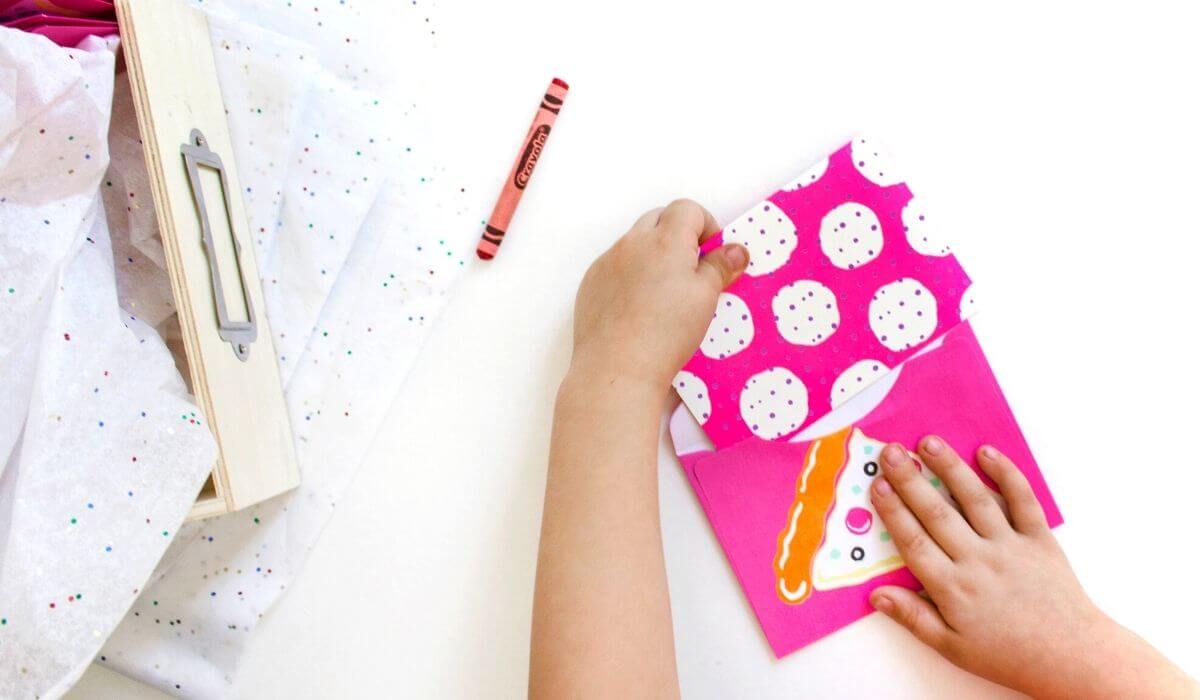 child putting party invitation in envelope