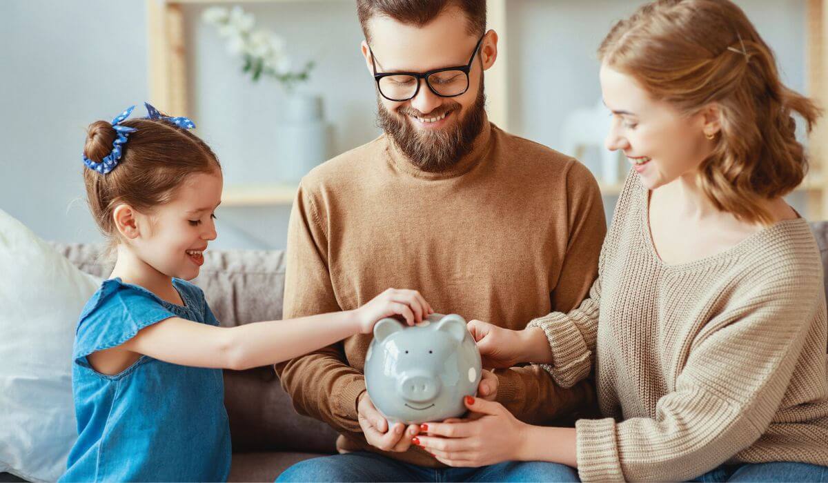 child with parents putting coin in piggy bank