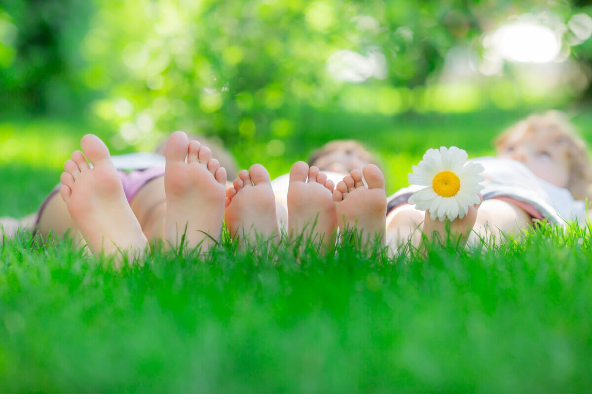 three people lying on the grass so you can see the base of their feet