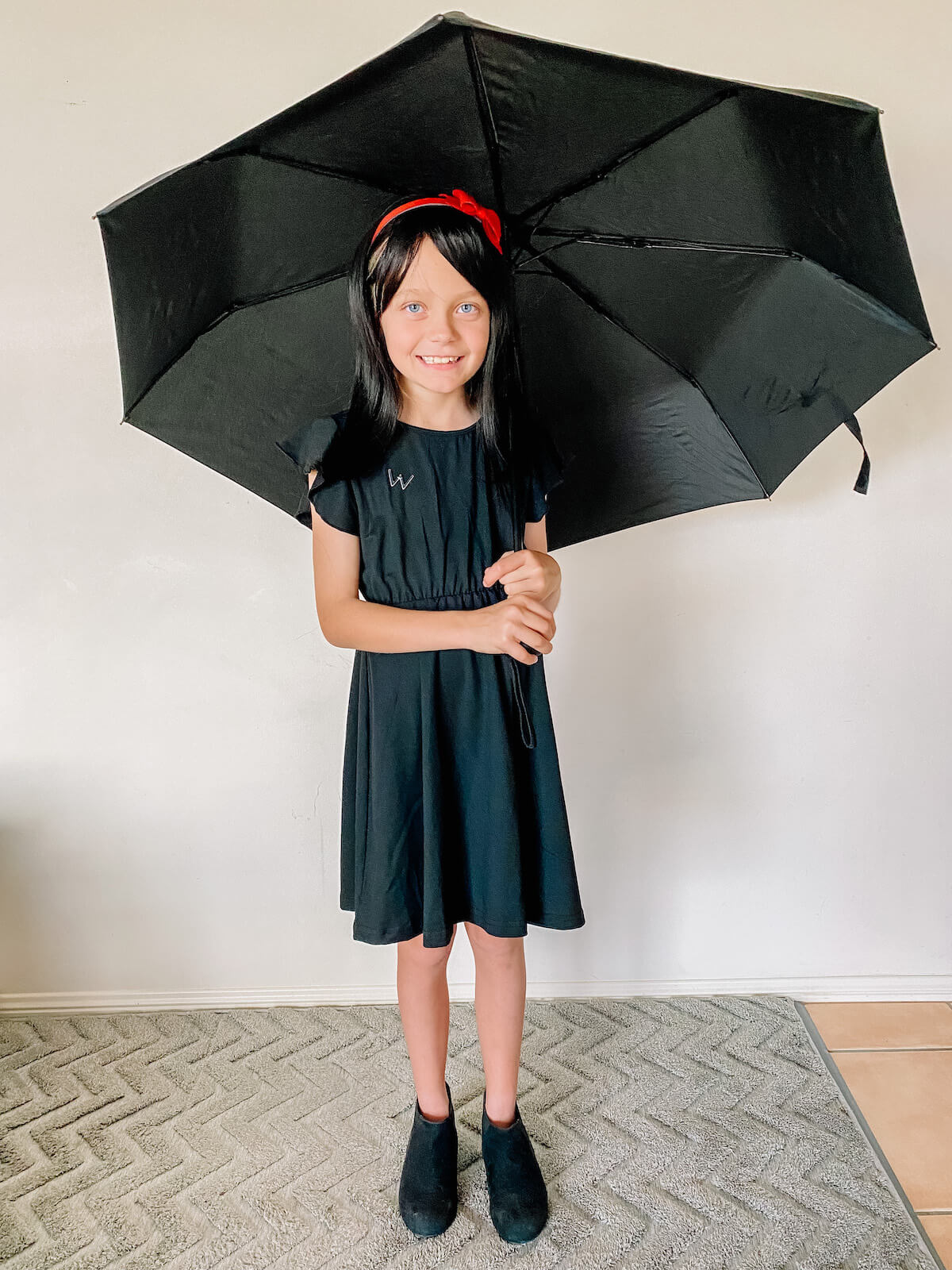 Child with open umbrella dressed as Morrigan Crow from Nevermoor