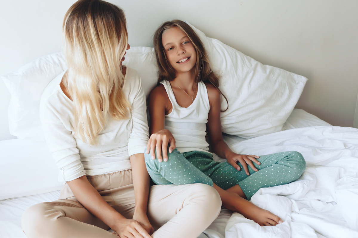 Mom with her tween daughter relaxing in bed,