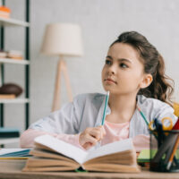 older child writing in journal at a desk