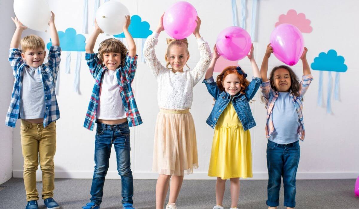 kids at birthday party holding balloons above their heads