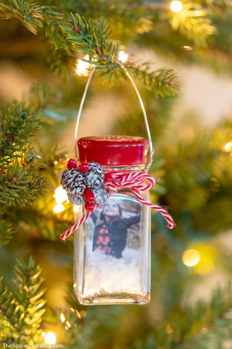 diy salt shaker snow globe ornament with a photo inside hanging from a christmas tree.