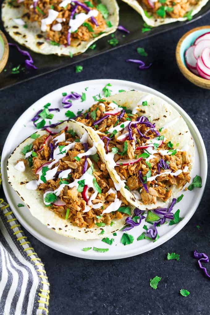 vegan jackfruit tacos on a plate on a dark table