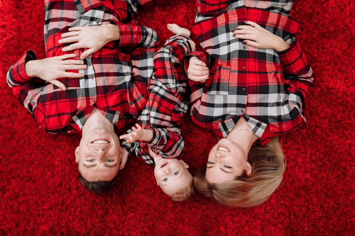 a family laying on the floor wearing matching checkered pjs