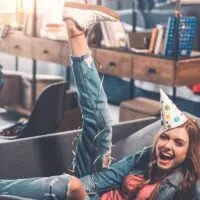 a woman with a party hat on with her leg in the air on the couch