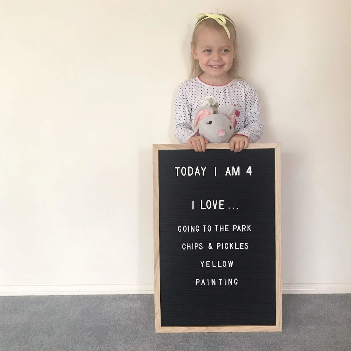 child holding a large letterboard to celebrate her 4th birthday with her favourite things listed.