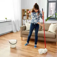 teenage girl mopping polished wooden floorboards