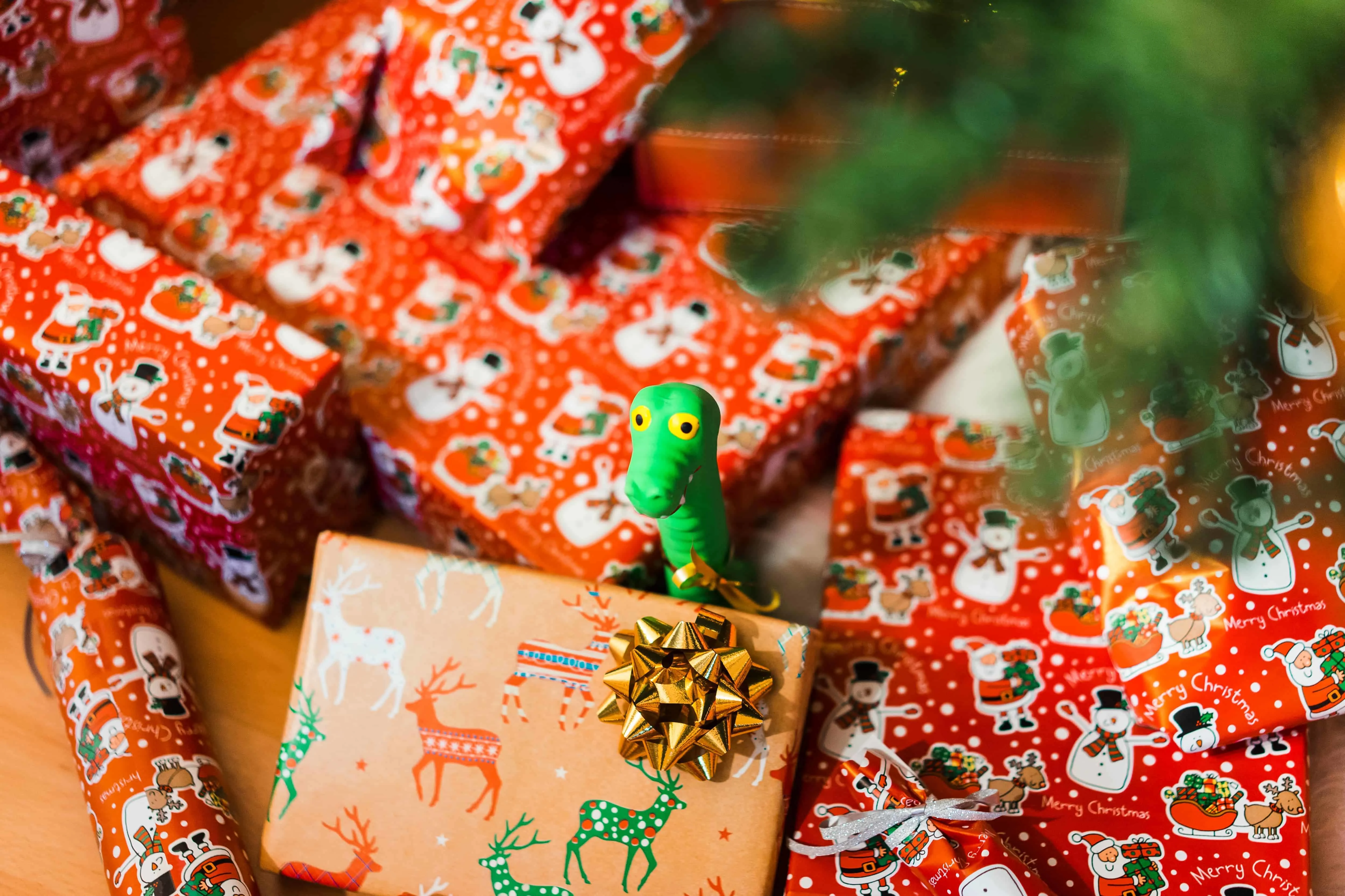 christmas gifts under tree with toy dinosaur