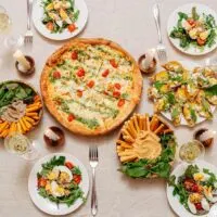 table with pizza, side dishes and wine