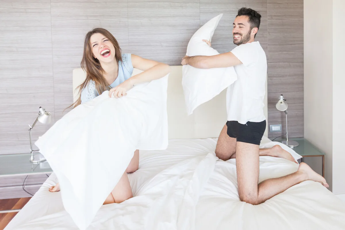 couple having a pillow fight on their bed