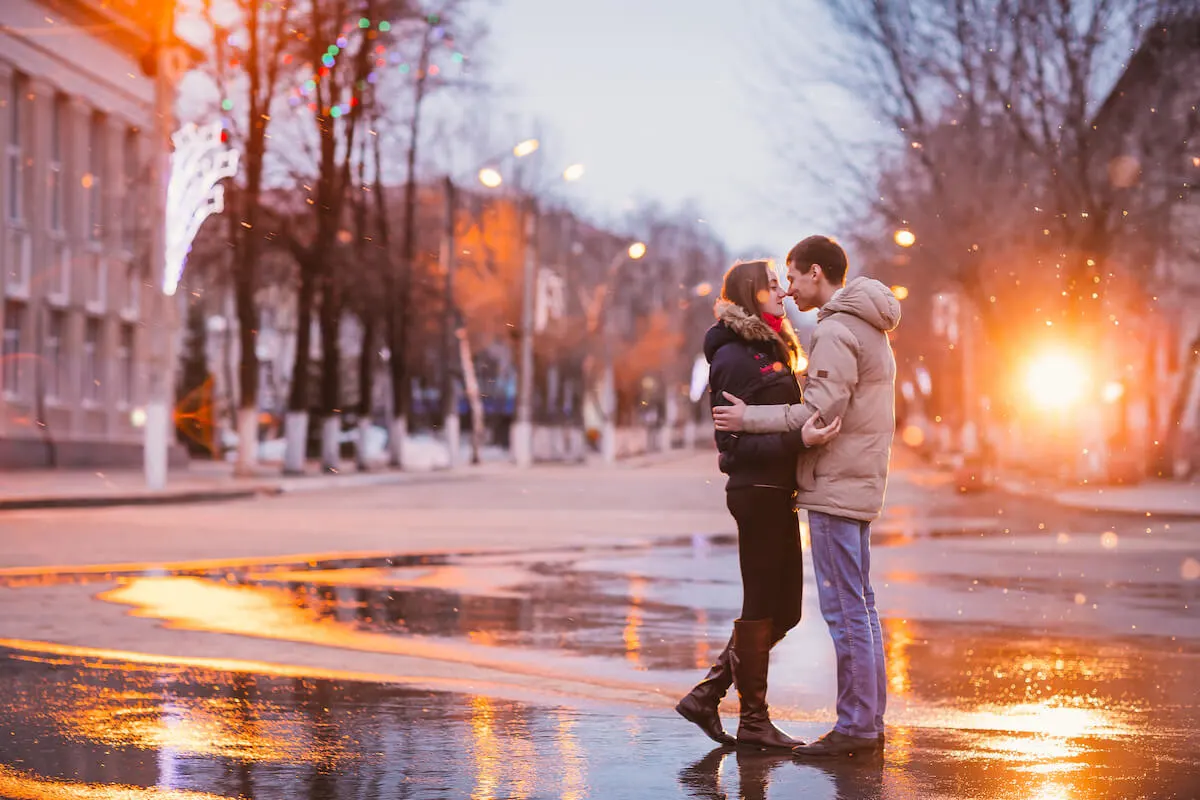 couple cuddling in the rain on a street