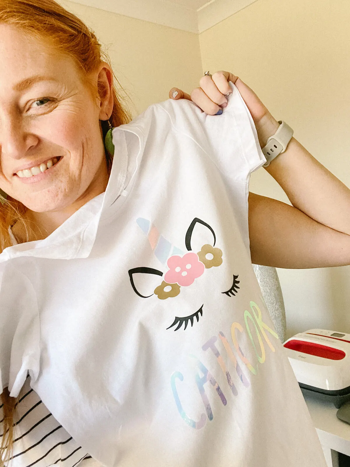 Holly holding a white t-shirt with an iron on vinyl design of a unicorn