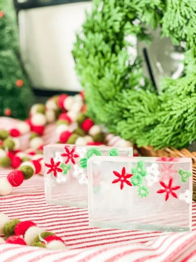 homemade christmas soap bars sitting on a red and white cloth with a wreath in the background.