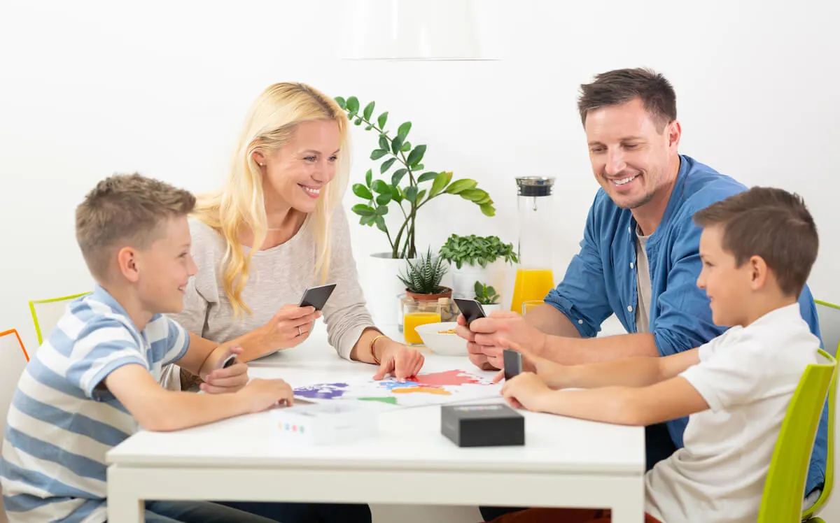 family of four playing a card game at a small white table