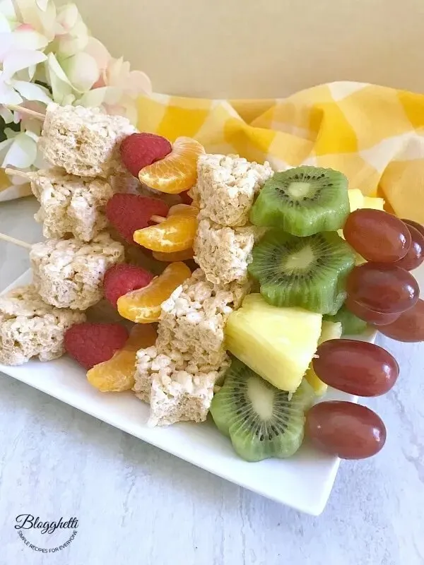 rice krispy kaboobs with kiwi fruit and grapes stacked on plate