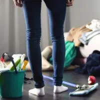 woman standing in front of a pile of mess with bucket of cleaning supplies