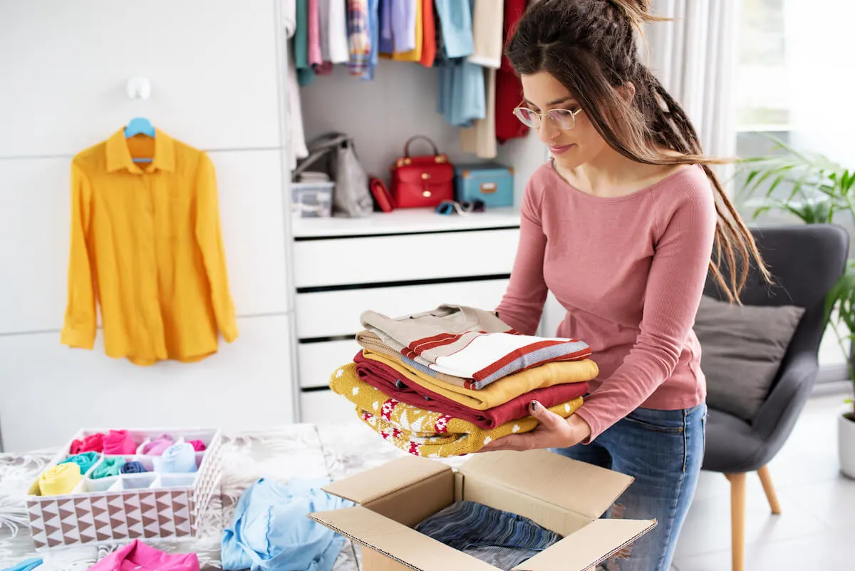 woman sorting unwanted clothing into a box for donating