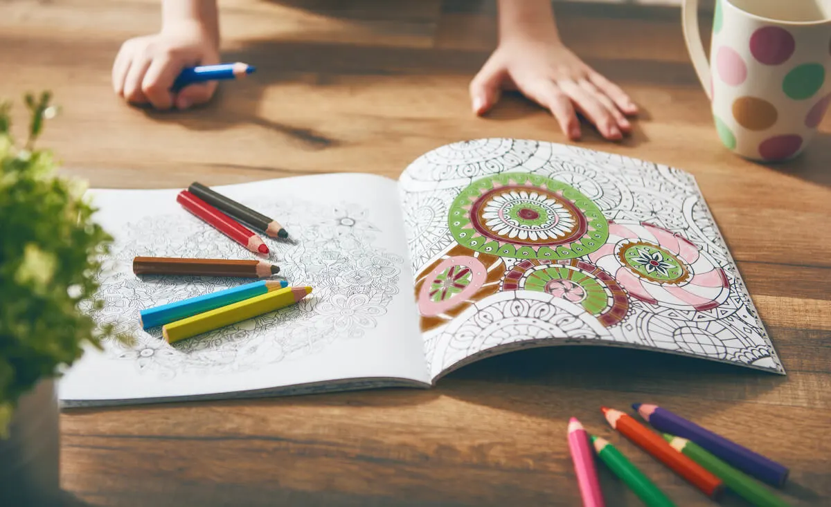 colouring book open with half finished colouring page of mandalas