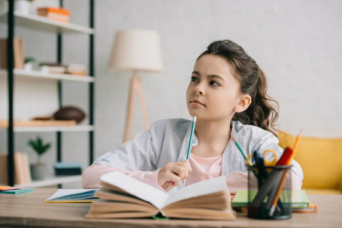 young girl sitting at a table in the family room with a journal open