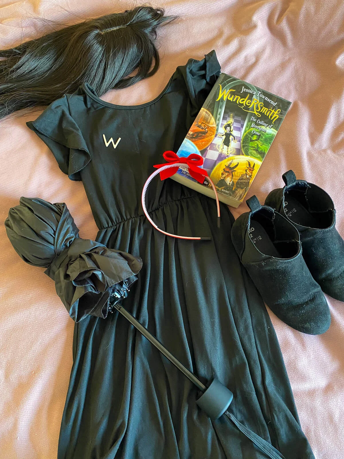 Dress, umbrella, headband, boots and book on bed