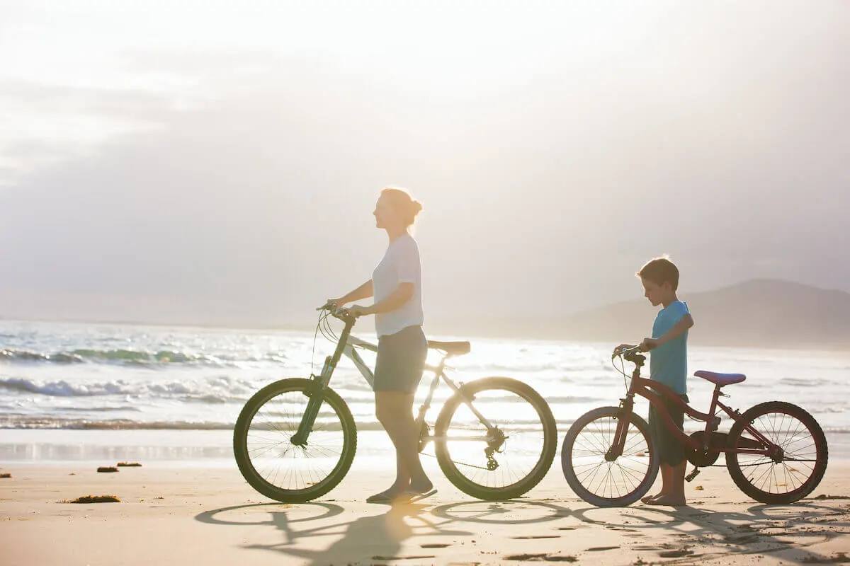 mother and son riding bikes on the beach early in the morning