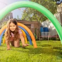 young girl crawling under pool noodle tunnel