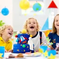 space party theme with three kids around a cake