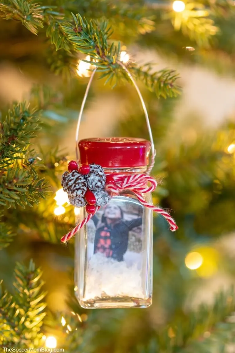 diy salt shaker snow globe ornament with a photo inside hanging from a christmas tree.