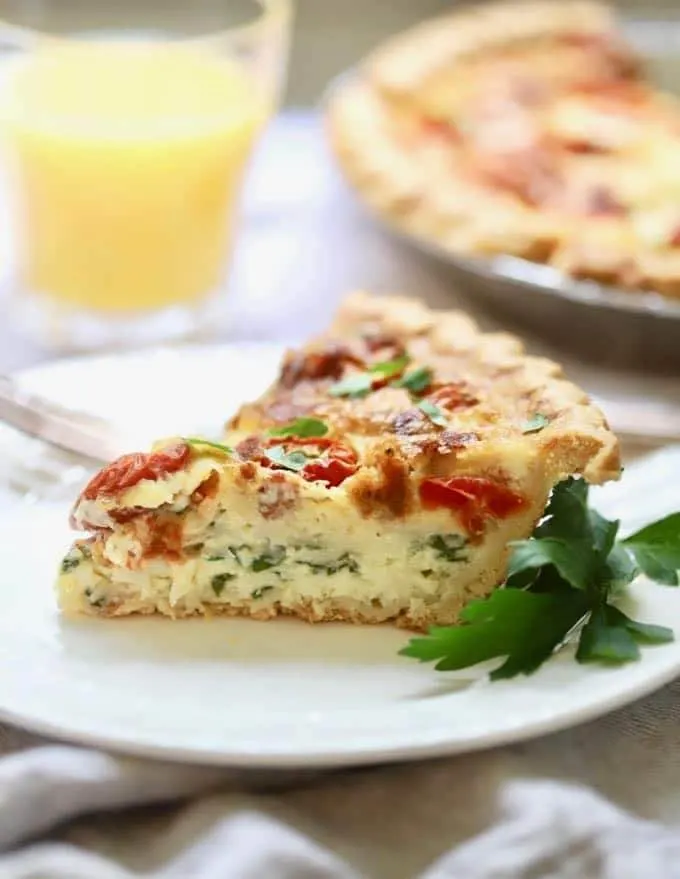 spinach bacon quiche cut into a slice on plate