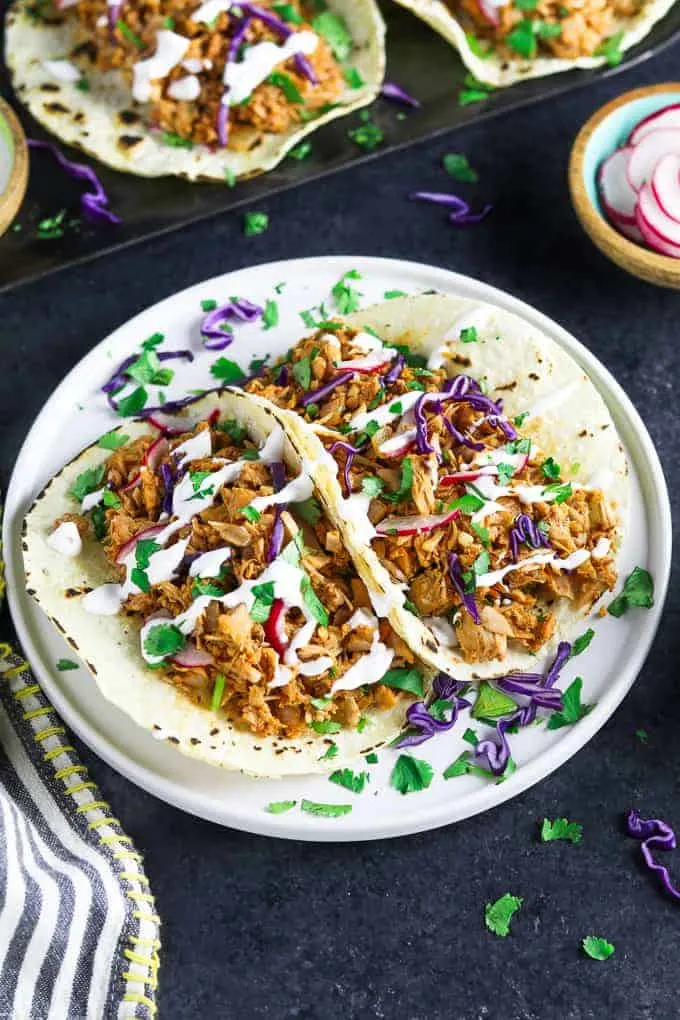 vegan jackfruit tacos on a plate on a dark table