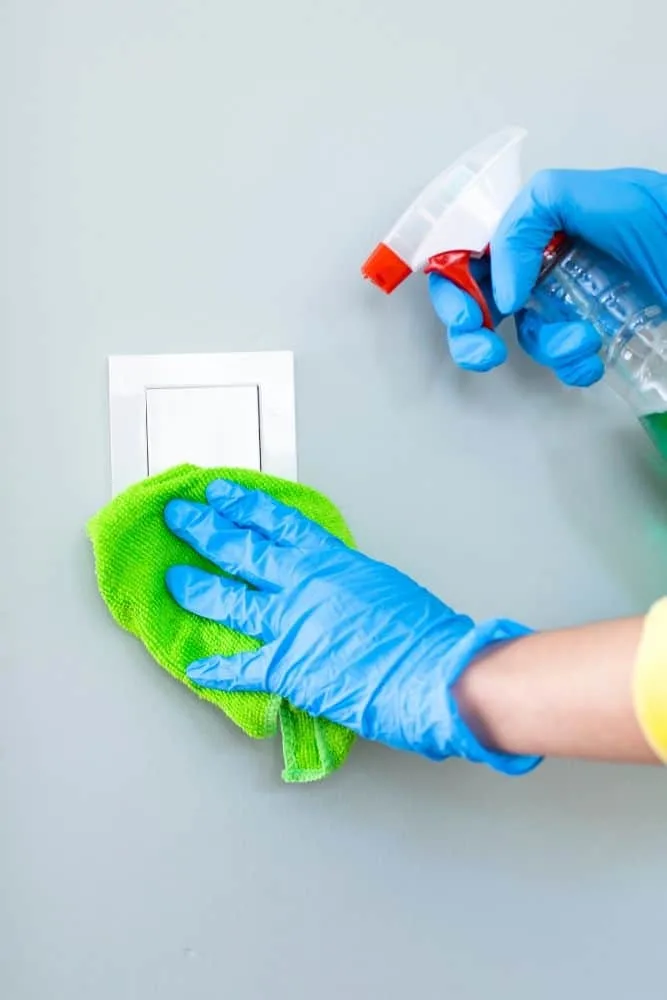 Cleaning a light switch with a cloth and spray