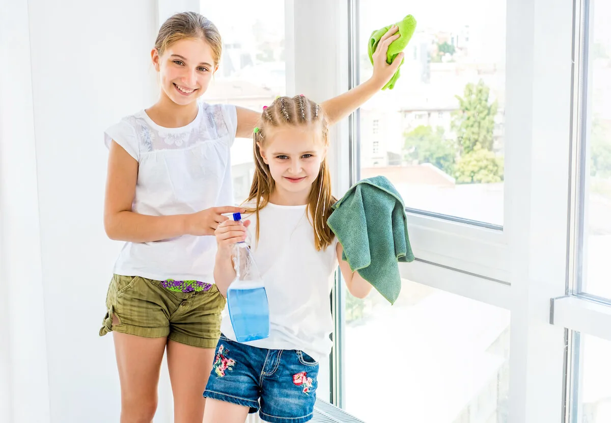 two tween girls with cloths and cleaning spray preparing to clean windows