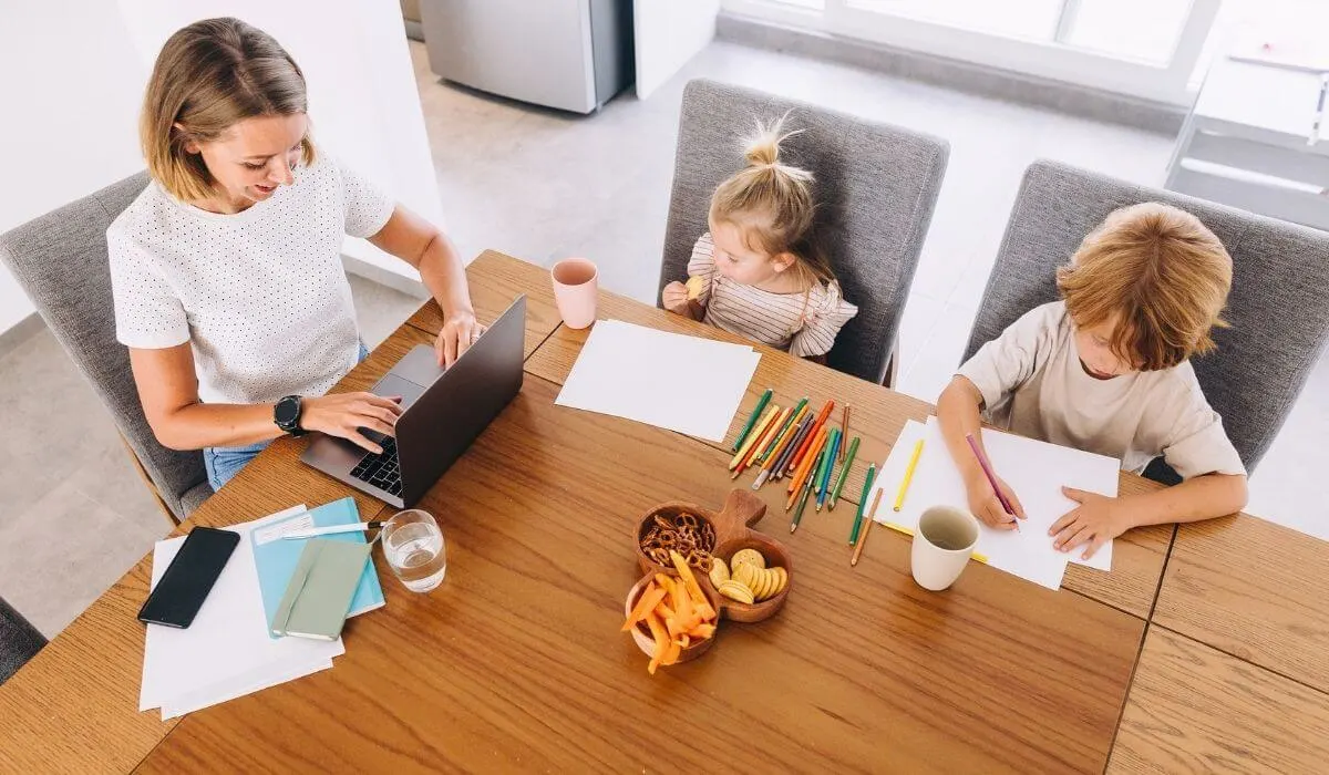 mother working at kitchen table alongside her 2 children